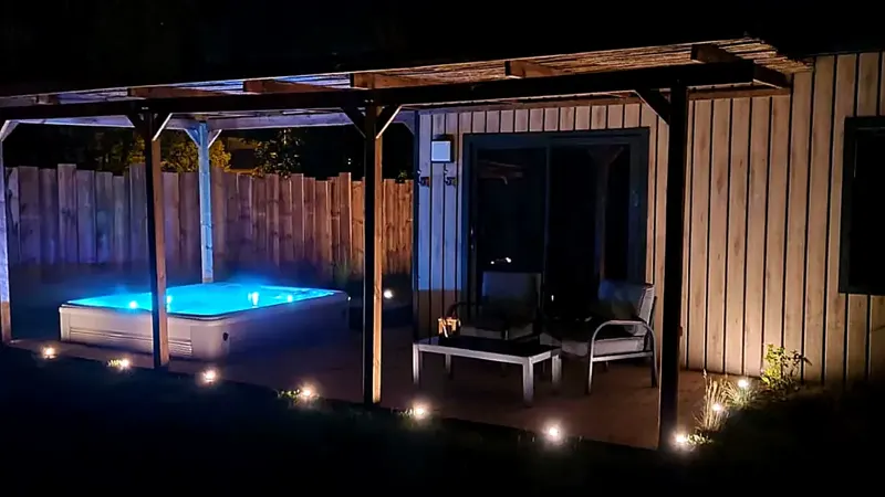 Un cottage en bois et son jacuzzi éclairé à la nuit tombée