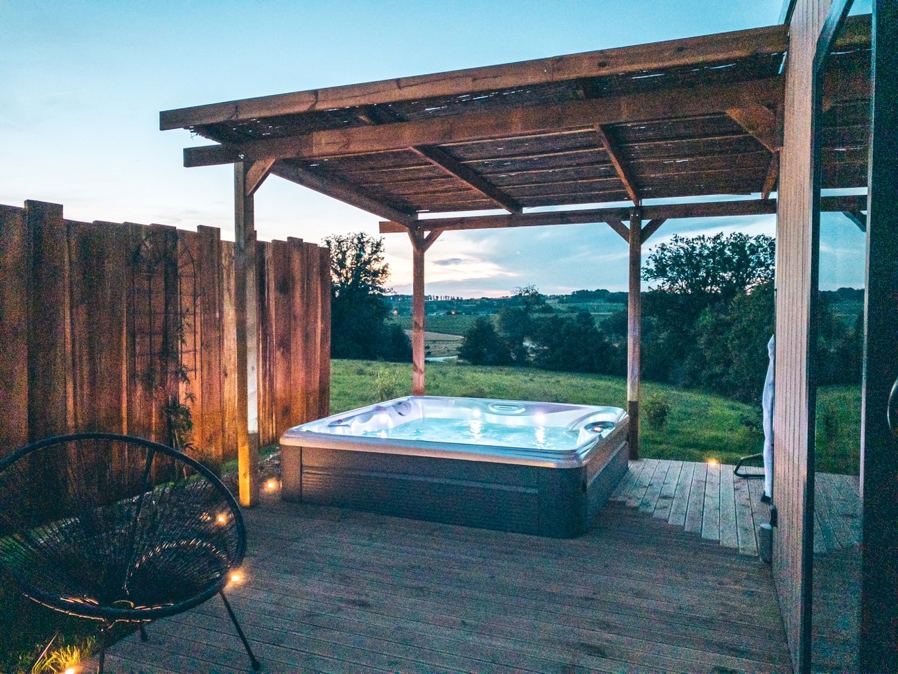 Terrasse du cottage Le Chêne avec fauteuil en fil, jacuzzi privatif et vue sur la campagne vosgienne