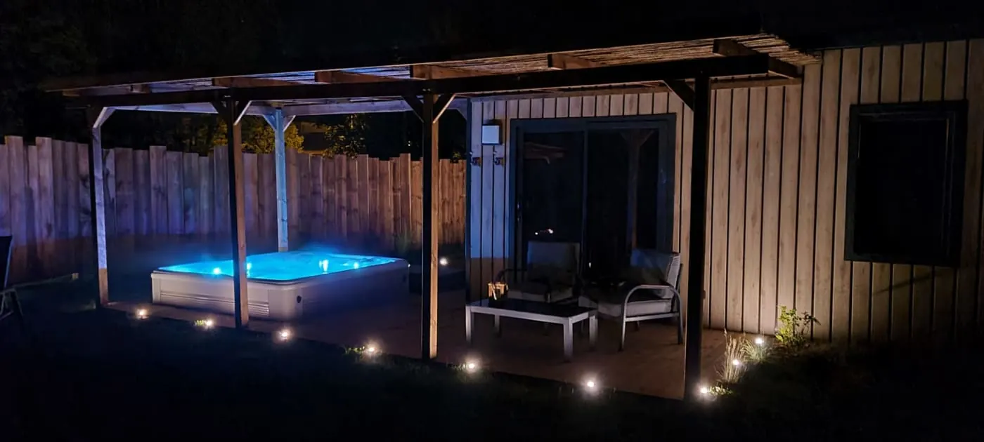 Jacuzzi privatif et cottage éclairés dans la nuit