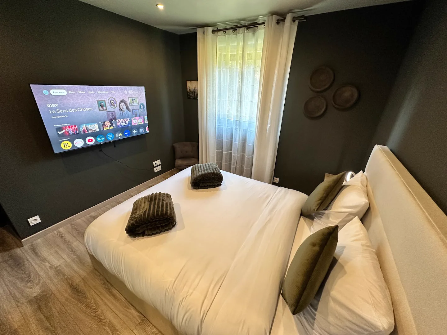 Première chambre : lit double et télévision · L’Écrin de la Forêt