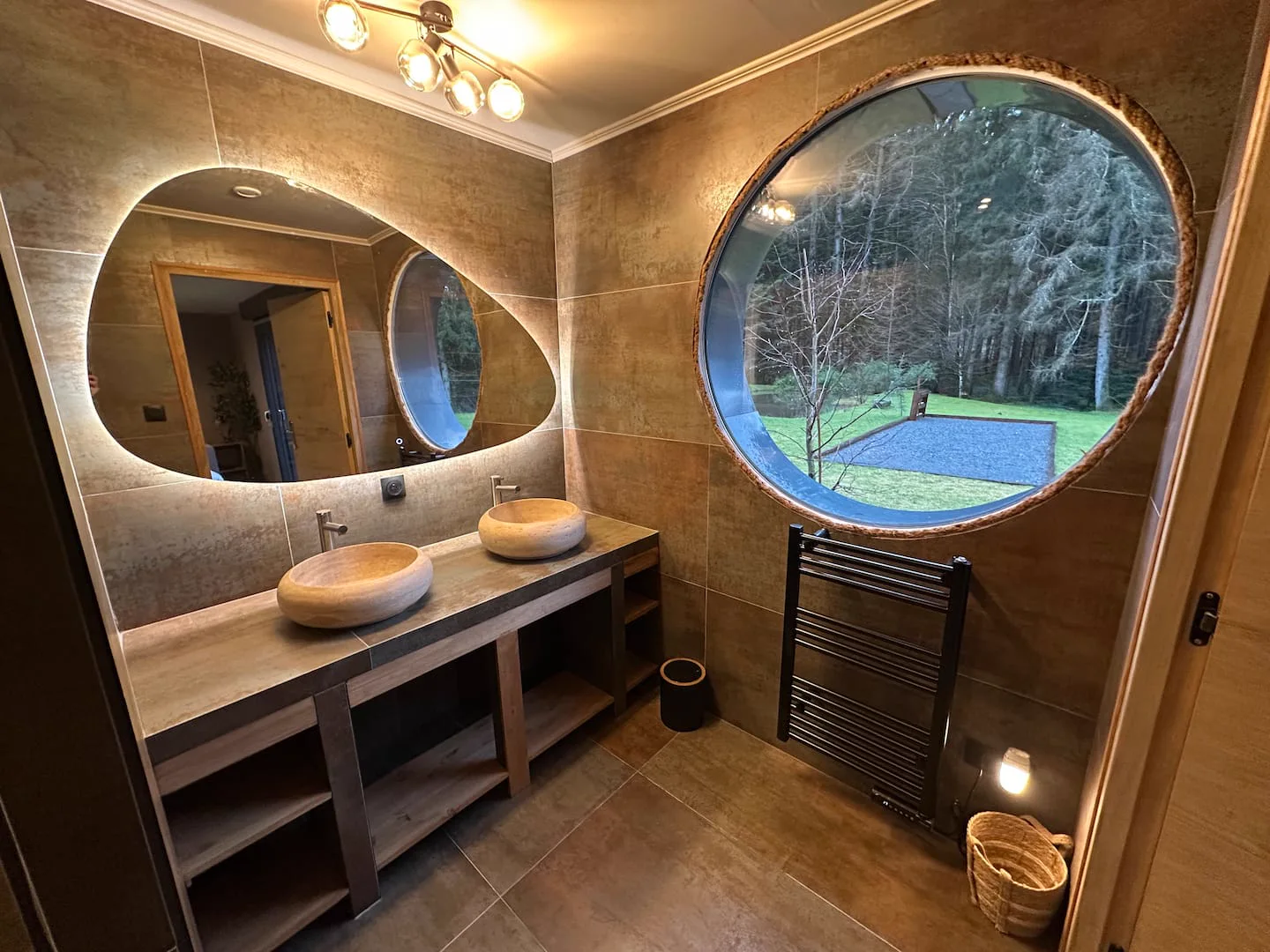 Salle de bain avec fenêtre ronde et double vasque · L’Écrin de la Forêt