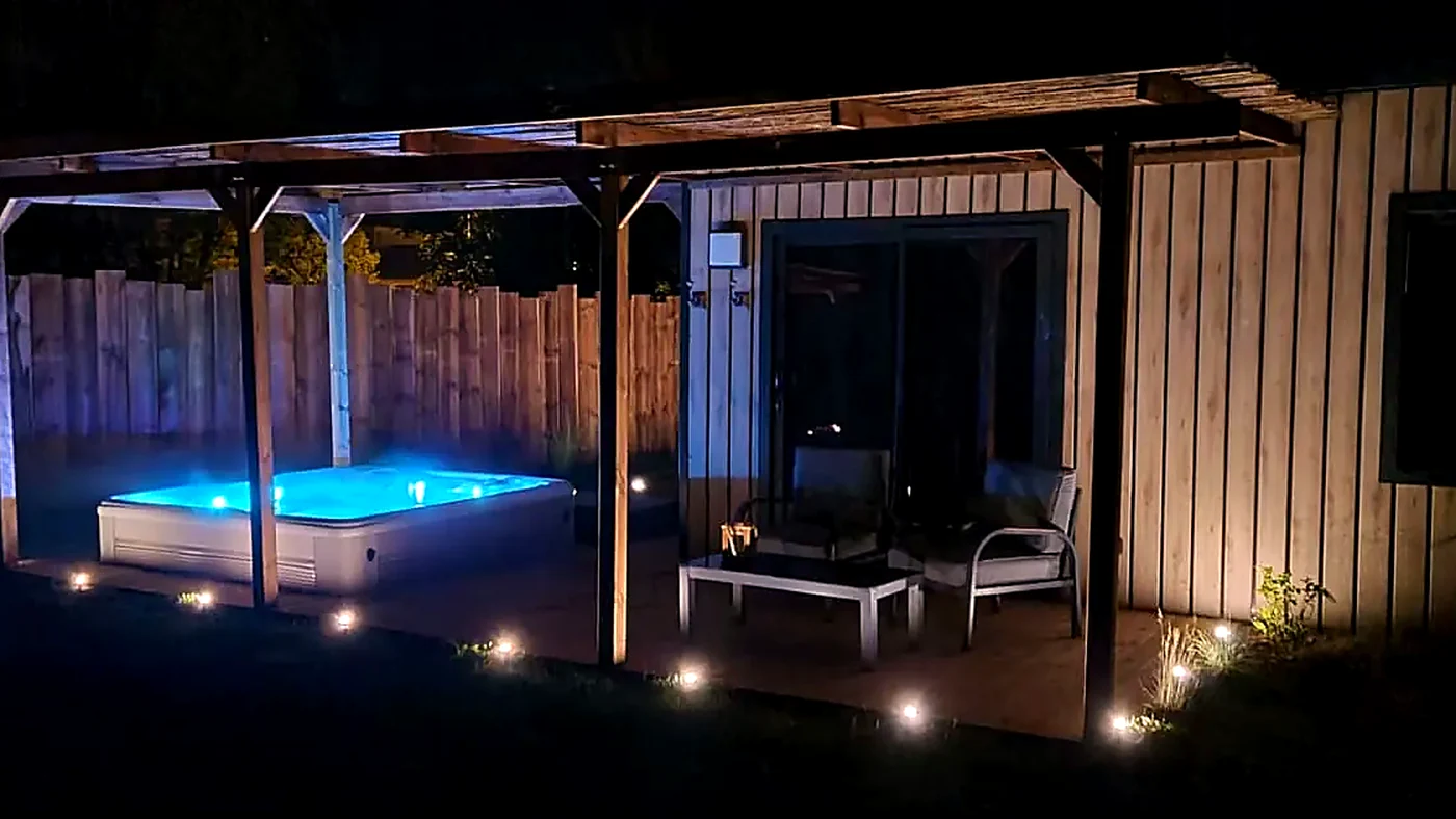 Jacuzzi réel éclairé le soir devant un cottage du Domaine